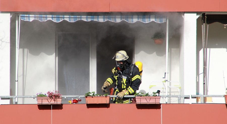 Brandschaden sanieren - Feuerwehrmann auf Balkon vor Wohnung