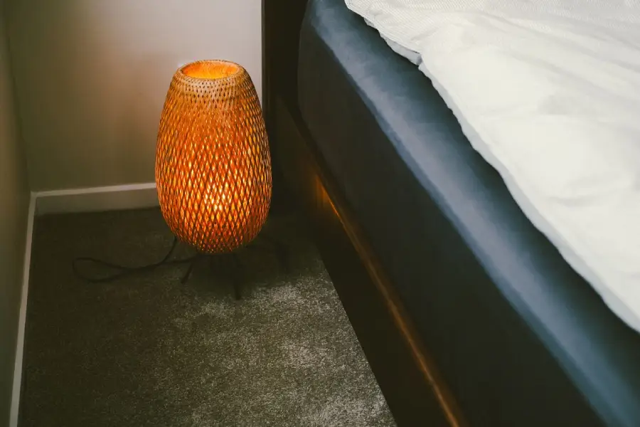 Foto eines Betts mit Lampe ohne Spannbettlaken auf Matratze