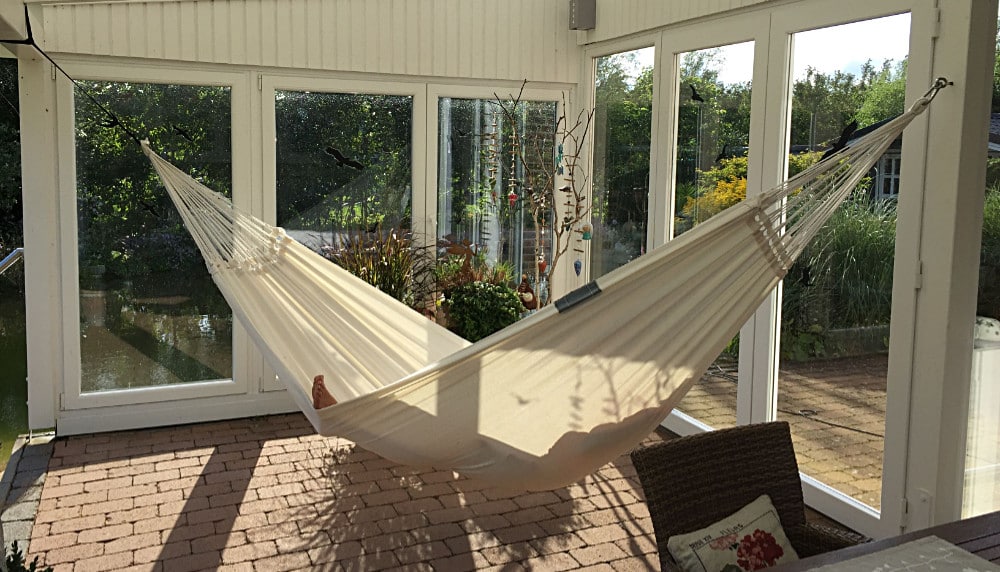 Entspannen im Garten in der Hängematte im Wintergarten mit Blick auf den Teich